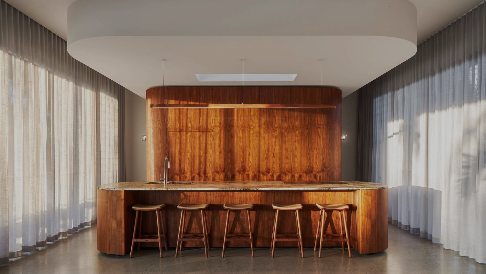 Walnut feautre kitchen with curved island bench and custom made timber lighting hanging above the island.