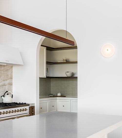 Minimal kitchen interior with a Tenn Linear Timber Pendant hanging above a white bench