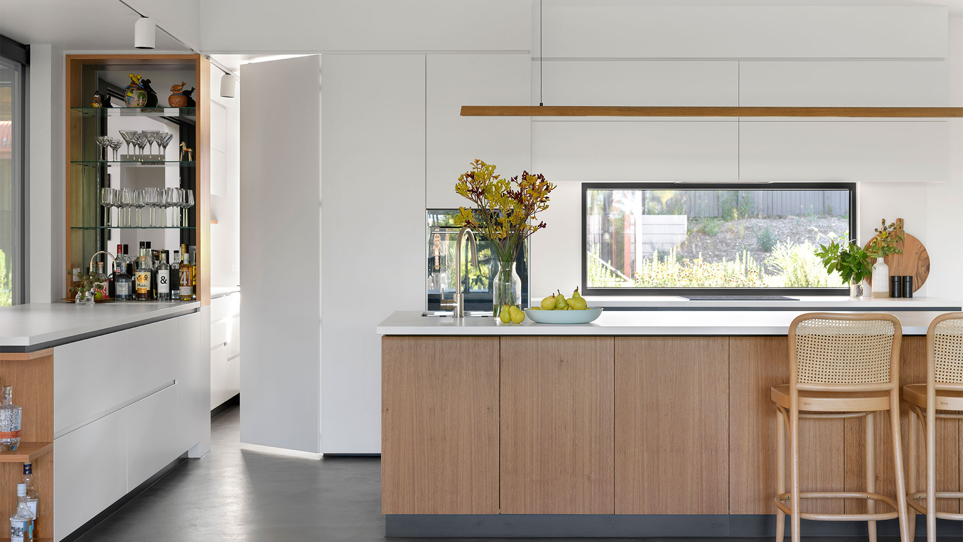 Interior kitchen with timber cabinetry on the kitchen island and a timber lighting pendant hanging above.