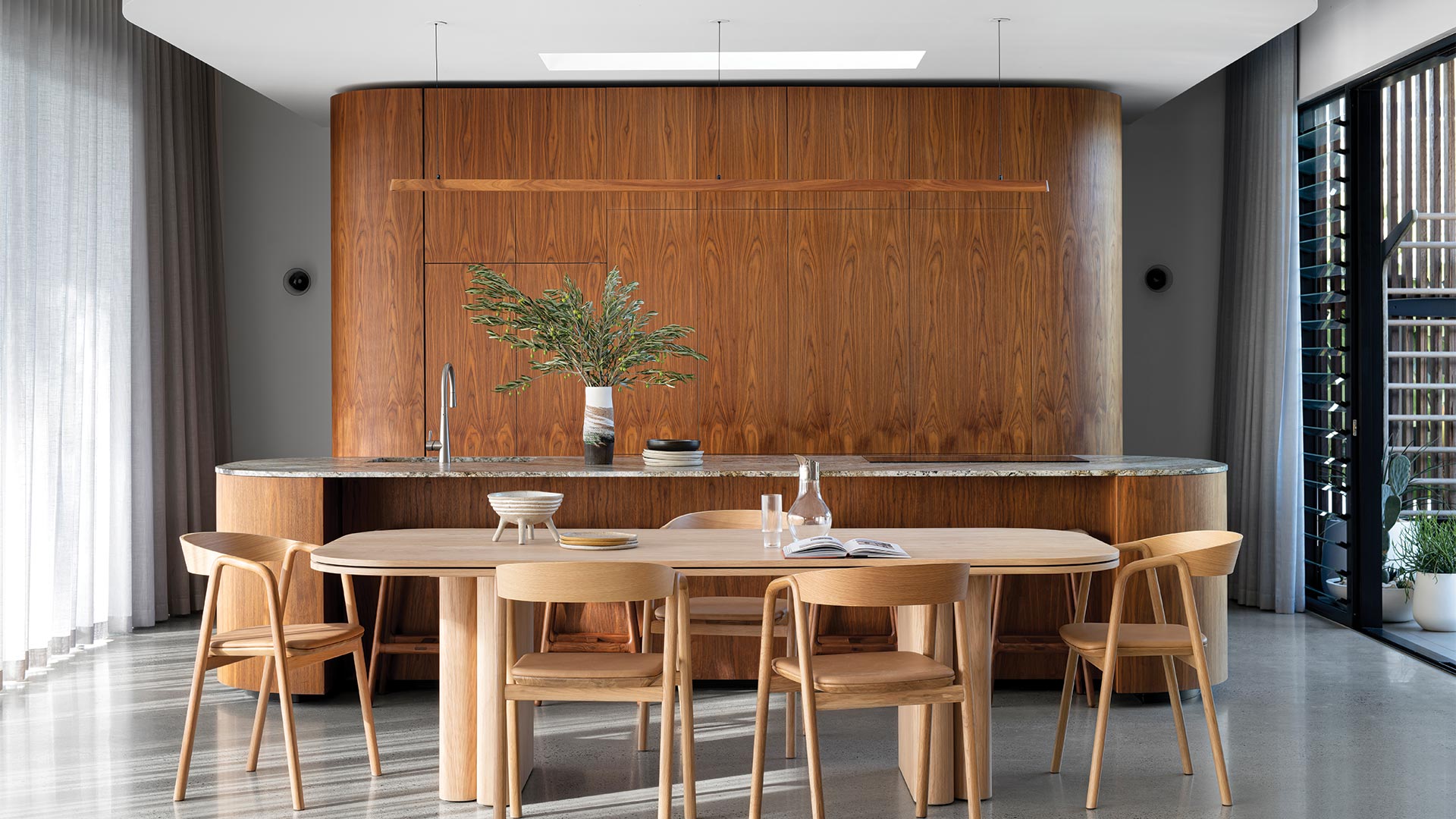 Walnut feautre kitchen with curved island bench and custom made timber lighting hanging above the island.